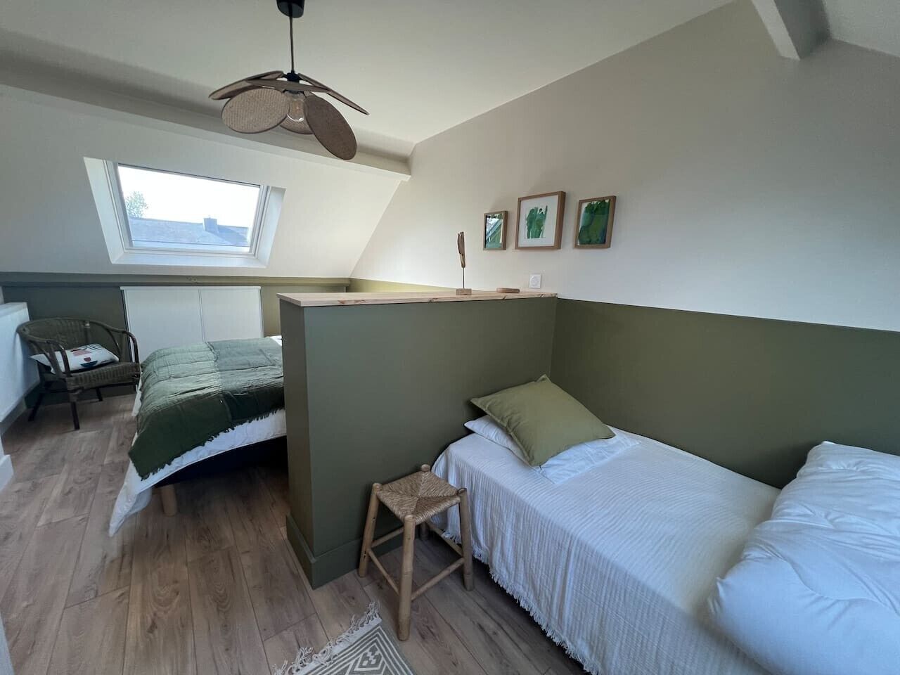 Une chambre avec un lit superposé, un petit tabouret, une chaise, une fenêtre et un ventilateur de plafond.