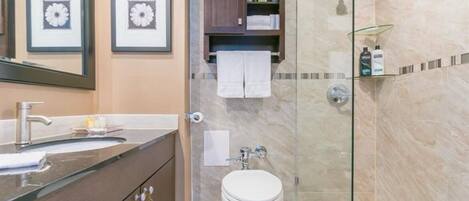 Un baño con lavamanos, inodoro y zona de ducha.