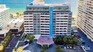 Un hotel de diverses plantes amb un atrium central, una zona d'aparcament i vistes a l'oceà.