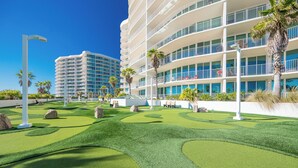 A modern hotel with a multi-story structure, a well-maintained lawn with landscaping, and a clear blue sky.