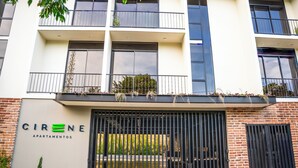 A multi-story building with balconies, a gated entrance, and a sign for 'CIRENE APARTAMENTOS'.