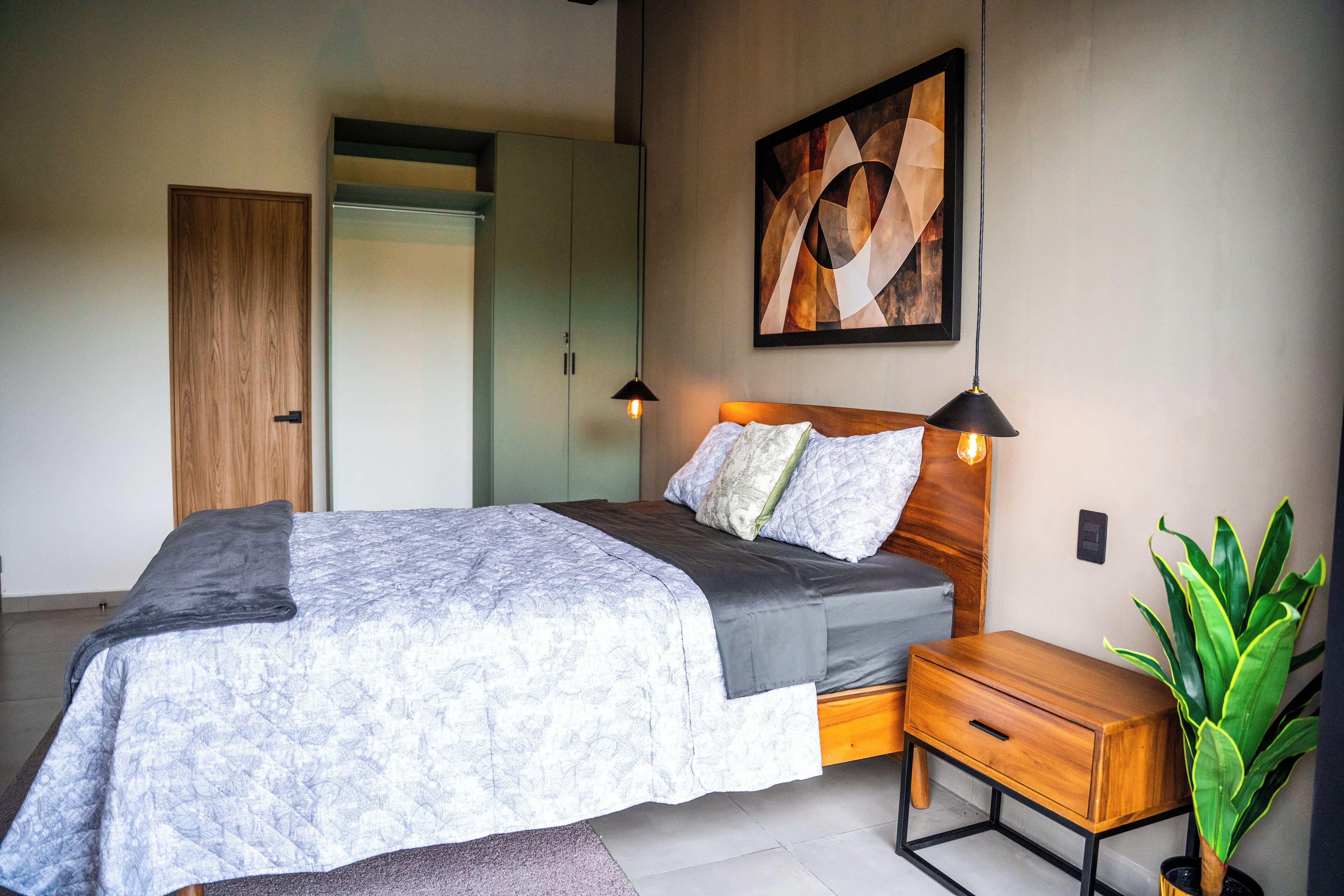 Un dormitorio con cama, mesita de noche y una planta en maceta.