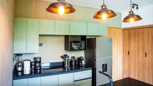A modern kitchen with a black countertop, stainless steel appliances, and green cabinets.
