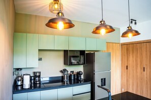 Una cocina moderna con encimera negra, electrodomésticos de acero inoxidable y armarios verdes.