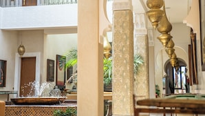 Eine Lobby mit einer Springbrunnen, Säulen und einem Balkon.