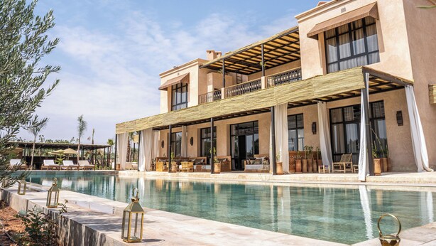 Ein modernes Resort mit großem Pool, Sitzgelegenheiten im Freien und einer überdachten Terrasse.