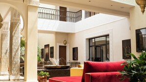 Ein geräumiger Innenhof mit einer roten Couch, einem Brunnen und einer hohen Decke mit Oberlichtern.
