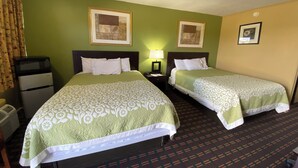A hotel room with two beds, a small kitchenette, and a single nightstand with a lamp. - Innkeeper Motel (Hamel)