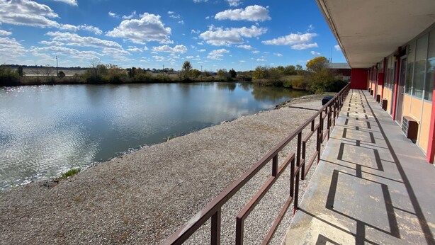 A riverside view with a gravel path and a building with a red facade. - Innkeeper Motel (Hamel)