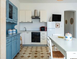 A compact kitchen with white cabinets, a blue cabinet, a microwave, a stove, and a sink. - Casa Onda Blu Fronte Mare nel Cuore di Torre Lapillo (Porto Cesareo)