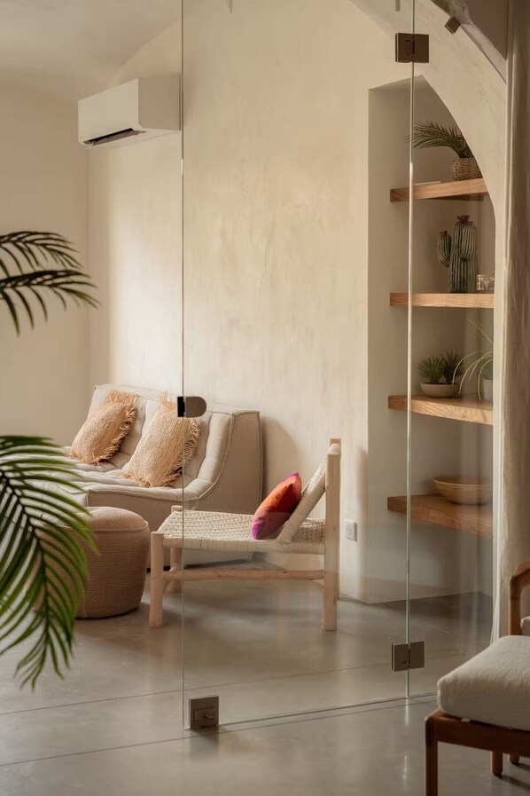 Una sala moderna con un sofá, un sillón y un separador de vidrio.