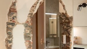 A room with exposed brick walls, a modern kitchen area, and a wooden dining table. - Montera Apartment with Pool (Bastia)