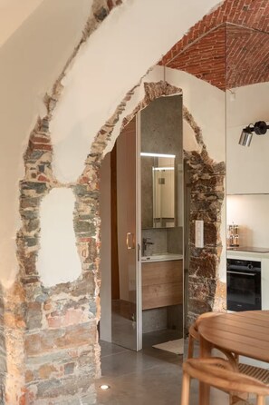 A room with exposed brick walls, a modern kitchen area, and a wooden dining table.