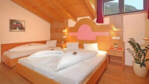 A wooden-paneled room with a bed, bedside table, and a potted plant.