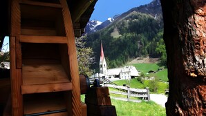 A wooden staircase leading to a room with a view of a mountain landscape, including a church and a white building.