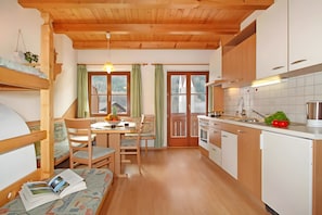 A cozy kitchen with wooden cabinets, a dining table with chairs, and a window with curtains.