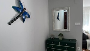 Una habitación con un aparador verde, un espejo en la pared y una libélula azul decorativa.