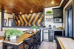 A modern kitchen with a wooden ceiling, a herringbone-patterned wall, and built-in appliances.