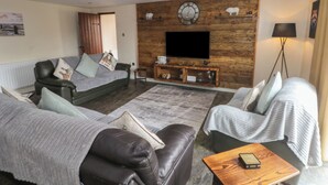 Ein modernes Wohnzimmer mit einer Ledersofa, einer Holzunterhaltungseinheit und einem Flachbildfernseher.