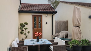 Eine Terrasse mit Tisch für vier Personen, umgeben von Korbstühlen.