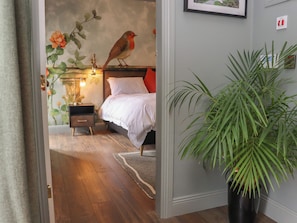 A bedroom with a bed, bedside table, lamp, and a wall-mounted picture of a bird. - ROBINS REST AT THE LODGE in Kilmacthomas, County Waterford (Kilmacthomas)