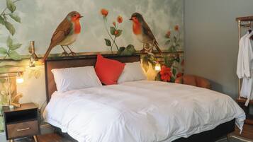 A bed with white bedding, a red pillow, and a nightstand with a lamp.