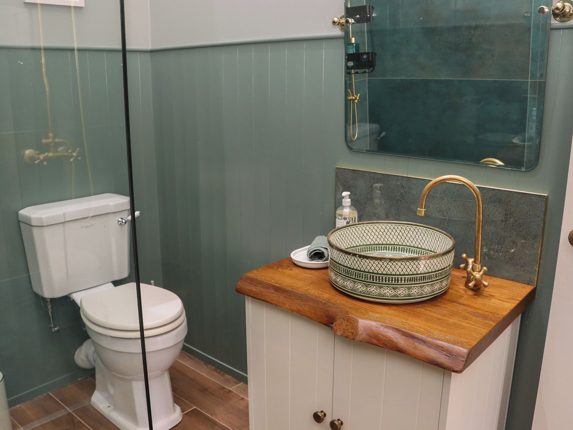Ein Badezimmer mit Toilette, einem Waschbecken mit dekorativer Schale und einem Spiegel.