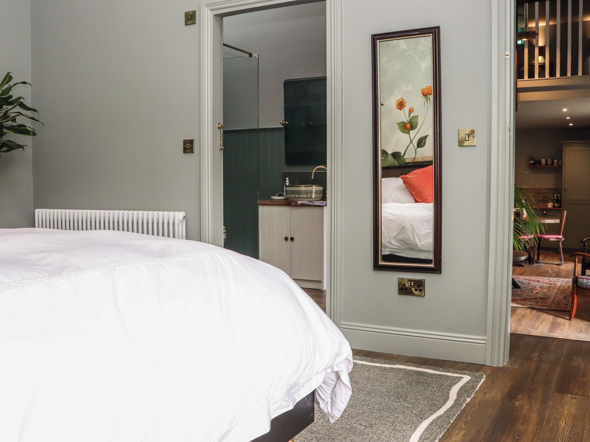 Une chambre à coucher avec un lit, un radiateur, un miroir et une vue sur la salle de bain.