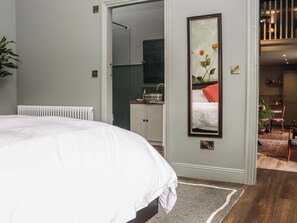Een slaapkamer met een bed, een radiator, een spiegel en uitzicht op de badkamer.