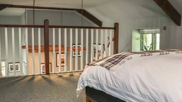 Ein Schlafzimmer mit einem großen Bett, Holzboden und Blick auf einen Balkon.