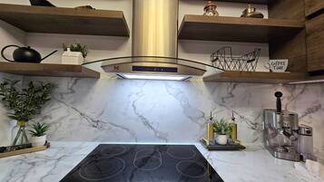 Una cocina moderna con estufa integrada, encimeras de mármol y cafetera.