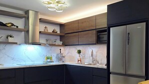 A modern kitchen with dark cabinetry, a stainless steel refrigerator, and a marble countertop. - Luxury stay at a budget friendly cost (San José)