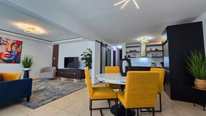 A modern living room with a dining area, a TV, and a kitchen in the background. - Luxury stay at a budget friendly cost (San José)