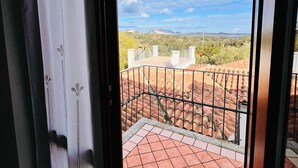Vista desde un balcón con tejas rojas, barandilla de metal y cielo despejado.