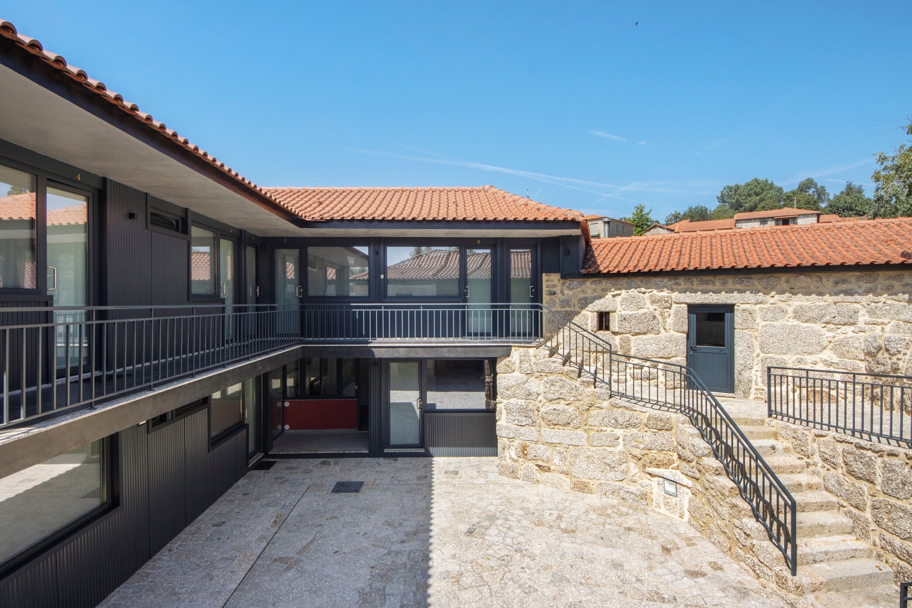 Un edificio moderno con facciata in pietra, un balcone e cielo sereno.