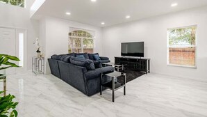 Un salon moderne avec un canapé gris, un téléviseur à écran plat et une table basse.