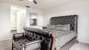 Une chambre à coucher avec un grand lit, un canapé en cuir et un ventilateur de plafond.
