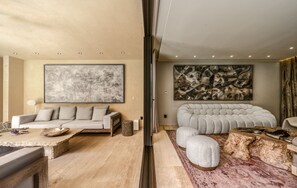 Uma sala de estar moderna com um sofá, um banquinho e uma mesa de centro, um grande quadro abstrato e uma mesa de centro de pedra.