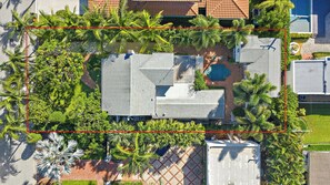 An aerial view of a property with a swimming pool, multiple buildings, and surrounding greenery.