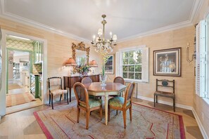 A dining room with a chandelier, a large mirror, and a window with a view.