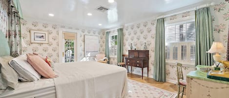 A bedroom with a bed, dresser, and a window with curtains.