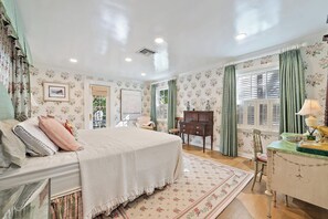 A bedroom with a bed, dresser, and a window with curtains.