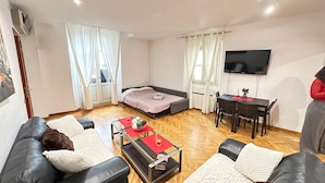 Una sala moderna con un sofá, una mesa de comedor y un televisor.