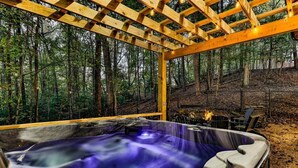 Un jacuzzi en un pabellón de madera rodeado de un bosque.
