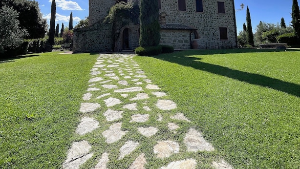 A stone building with a central courtyard, a tall cypress tree, and a clear blue sky. - Apartment 'Villa Tiberini 2' with Garden View, Shared Pool and Wi-Fi (Torrita di Siena)