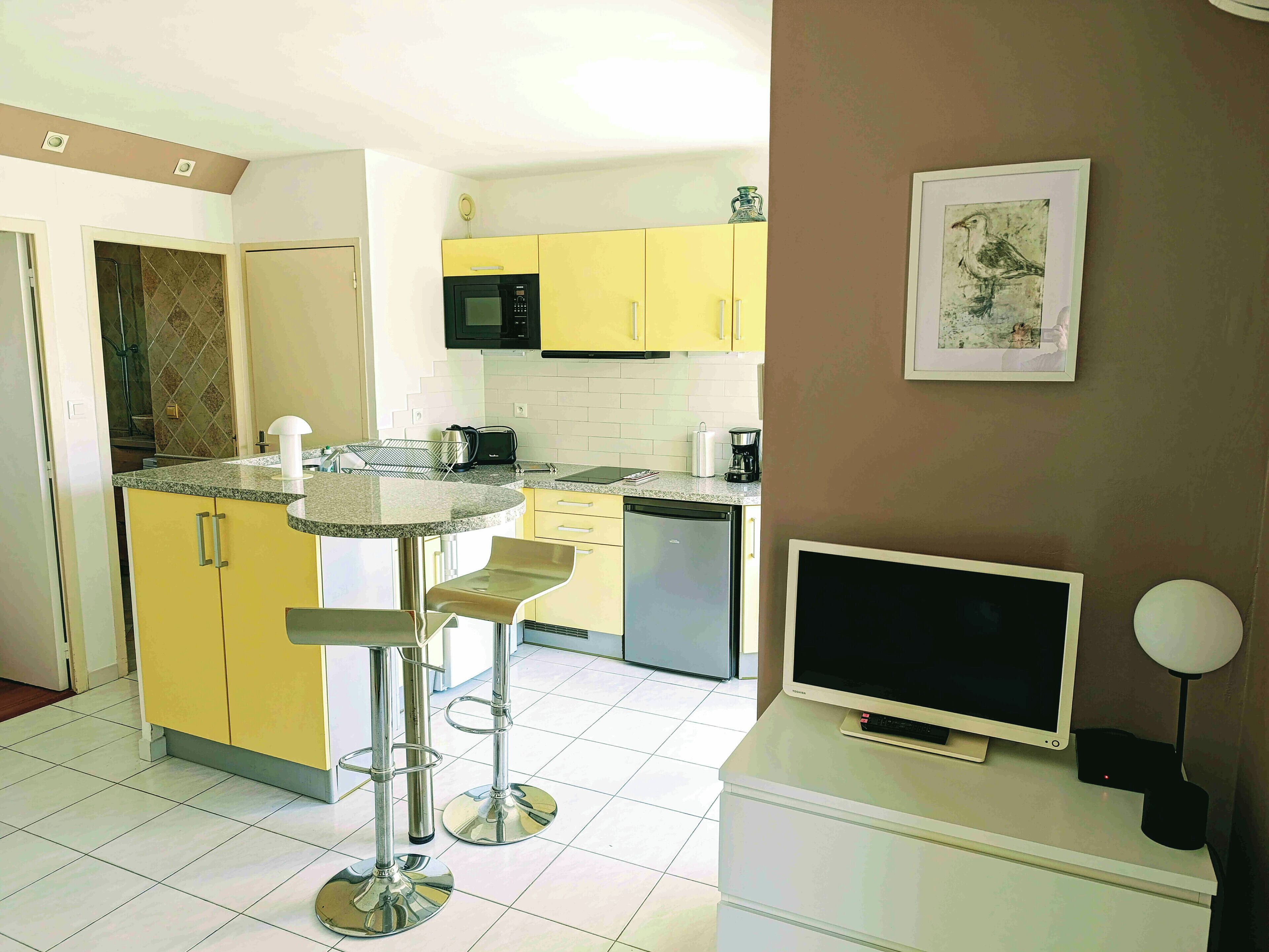 Una cocina compacta con una isla central, armarios amarillos, microondas y cafetera.