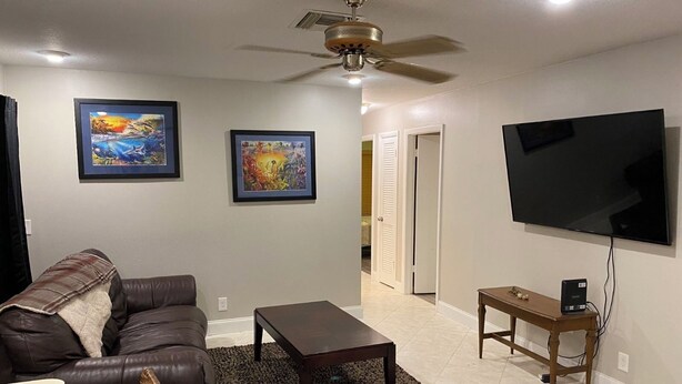 A living room with a sofa, a coffee table, a TV, and two framed artworks on the wall.