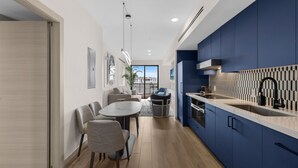 Une cuisine moderne avec des armoires bleues, un comptoir blanc et un robinet noir. On y trouve également un coin repas avec une table et des chaises.