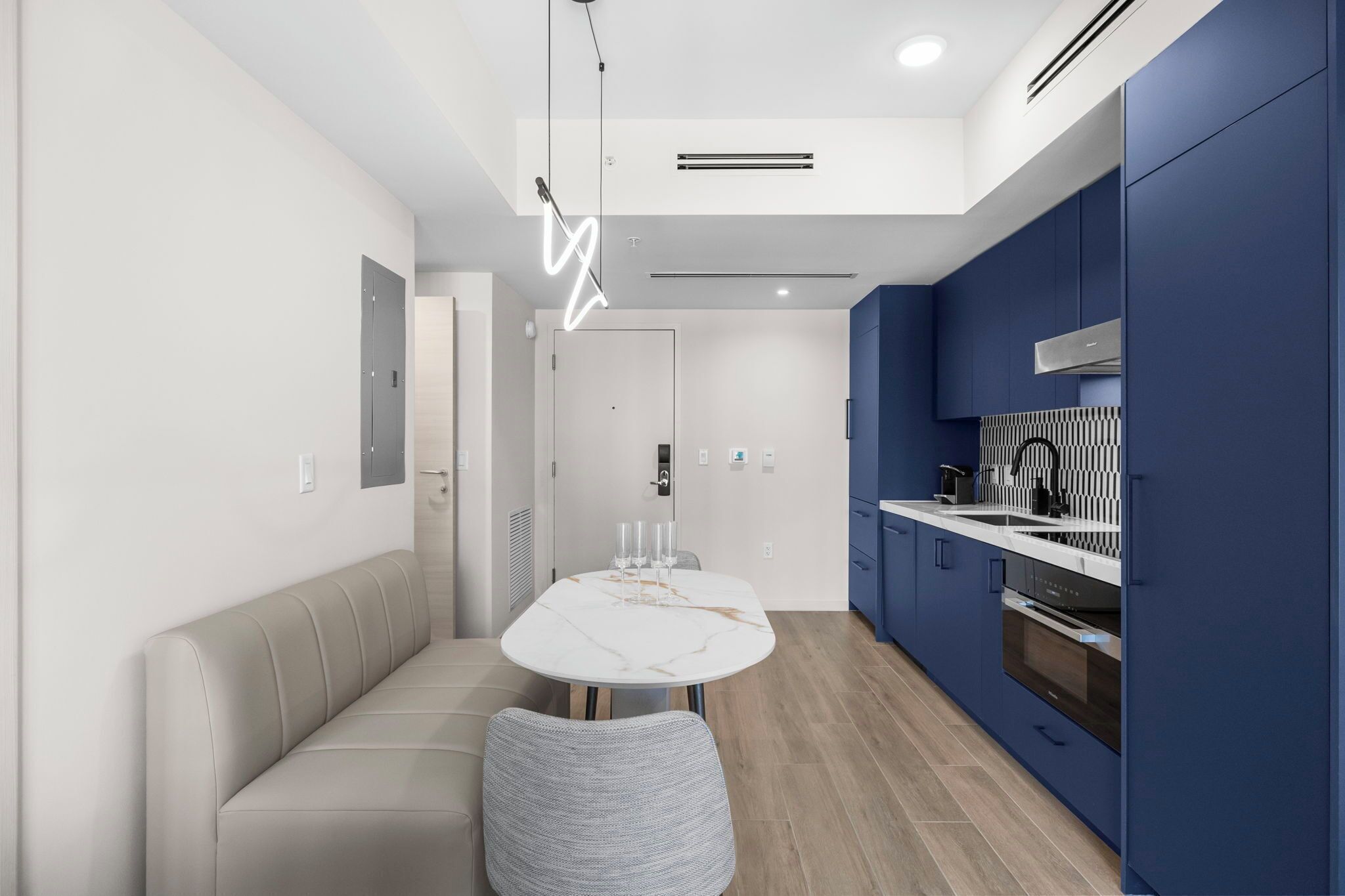 A modern kitchen with blue cabinets, a white countertop, and a built-in oven.