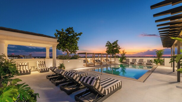 Un espace piscine aménagé sur le toit, avec des chaises longues et une pergola.